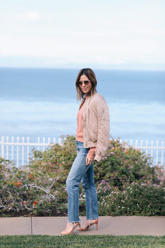 Peach bomber jacket with high-waisted denim and nude sandals