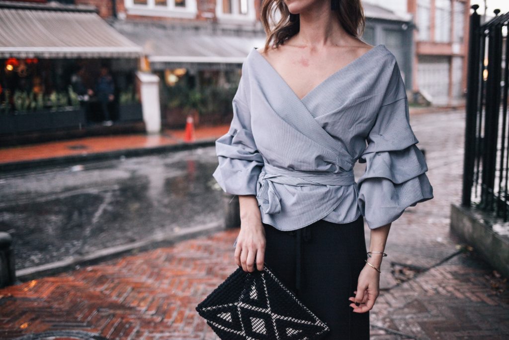 Blogger Mary Krosnjar wearing ruffled sleeved top and Sole Society Tasseled Woven Clutch