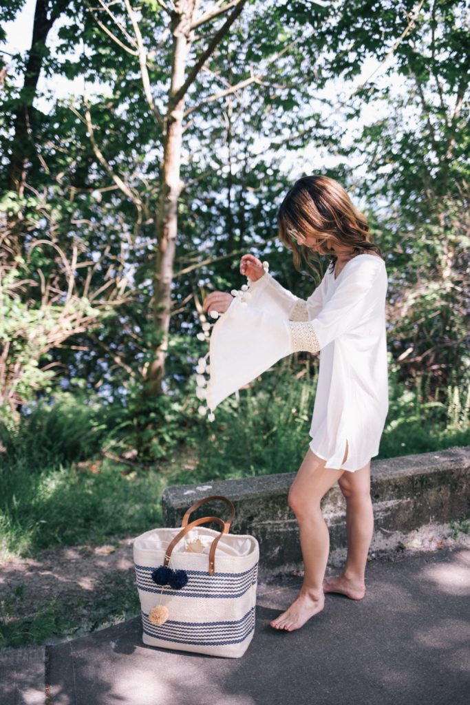 Blogger Mary Krosnjar wearing white beach cover-up and striped beach bag